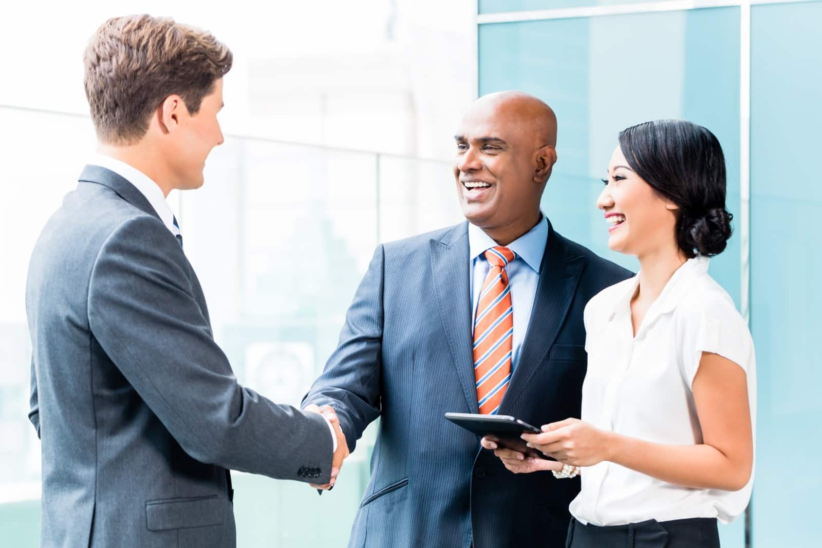 Businessman Shaking Hands With Younger Businessman While Woman Watches