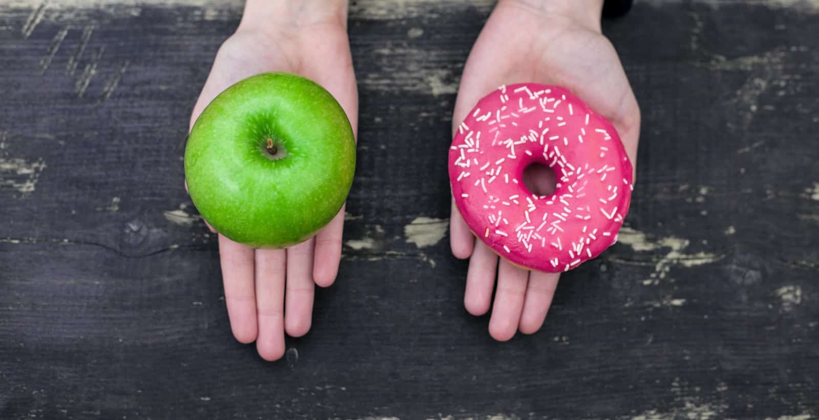 Hands Offering Green Apple Or Pink Donut On Black Background