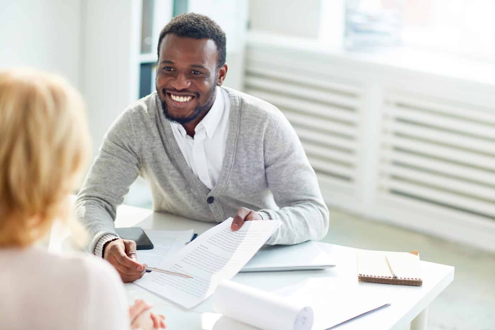 Smartly Dressed Man Pointing At Contract While Explaining It To Partner